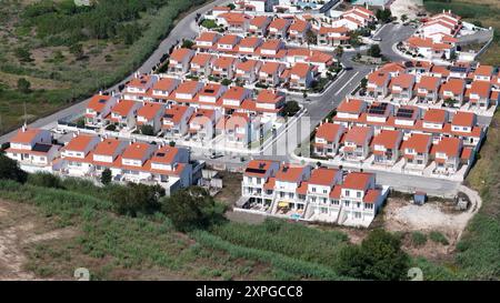 Une vaste communauté résidentielle comprend des rangées de maisons, chacune avec des toits rouges distinctifs, nichée au milieu d'une végétation luxuriante Banque D'Images