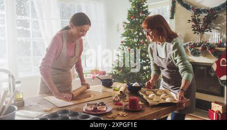 Portrait de mère adulte et fille préparant le dîner de Noël pour les invités. Belle femme et sa mère senior se liant tout en cuisinant, en parlant, en passant du temps ensemble pendant les vacances Banque D'Images