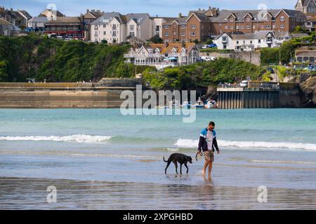 Un homme et son chien marchant le long du rivage sur Towan Beach à Newquay en Cornouailles au Royaume-Uni. Banque D'Images