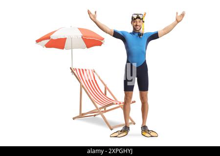 Portrait en pied d'un homme portant une combinaison de plongée, un masque et des palmes devant une chaise de plage et un parasol isolé sur fond blanc Banque D'Images