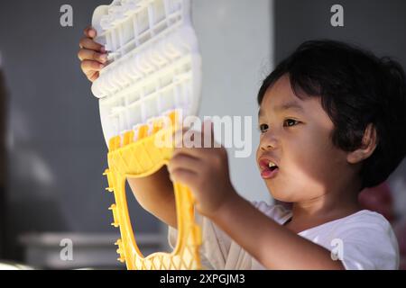 Un jeune garçon profondément concentré, engagé avec un jouet sous un doux éclairage du soleil matinal Banque D'Images