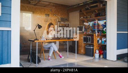 Programmation féminine hispanique sur ordinateur portable dans le garage à la maison. Jeune femme travaillant sur Innovative Software as A Service Startup for Business. Digital entrepreneur Starting Tech Company concept Banque D'Images