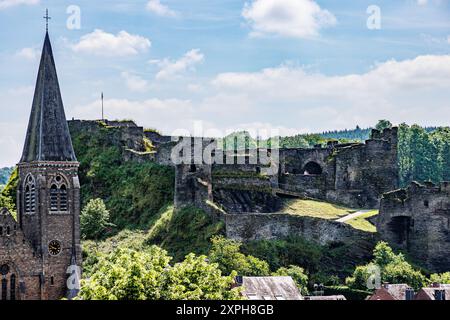 Ruines du château de la Roche-en-Ardenne sur colline et tour de l'église Saint-Nicolas, entourée d'arbres verdoyants, journée ensoleillée en Wallonie, Belgique Banque D'Images