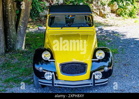 Vieille voiture de luxe avec carrosserie jaune et noire en vue de face, cabriolet avec capote souple, deux rétroviseurs, quatre phares blancs, journée d'été ensoleillée Banque D'Images