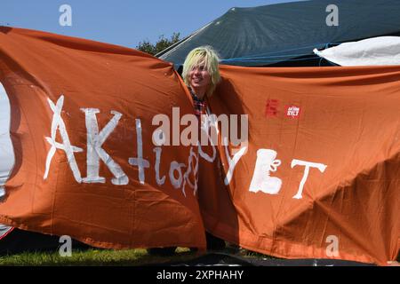 Tinnum, Sylt, Allemagne. 06 août 2024. Jonas Hötger (24 ans), co-organisateur du camp de protestation de Francfort, se tient derrière une banderole portant l'inscription 'Aktion Sylt' au camp de protestation punk sur le Festwiese. Jusqu'au 1er septembre, les participants au camp du groupe 'Aktion Sylt' veulent manifester sur l'île pour la solidarité, la justice climatique et contre la gentrification, entre autres choses. Crédit : Lea Albert/dpa/Alamy Live News Banque D'Images