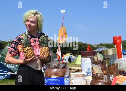 Tinnum, Sylt, Allemagne. 06 août 2024. Jonas Hötger (24 ans), co-organisateur du camp de protestation de Francfort, se tient dans la « cuisine » du camp de protestation punk sur le Festwiese. Jusqu'au 1er septembre, les participants au camp du groupe 'Aktion Sylt' veulent manifester sur l'île pour la solidarité, la justice climatique et contre la gentrification, entre autres choses. Crédit : Lea Albert/dpa/Alamy Live News Banque D'Images