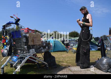 Tinnum, Sylt, Allemagne. 06 août 2024. Un participant au camp de protestation punk se tient à côté d'un chariot dans la prairie du camp. Jusqu'au 1er septembre, les participants au camp du groupe 'Aktion Sylt' veulent manifester sur l'île pour la solidarité, la justice climatique et contre la gentrification, entre autres choses. Crédit : Lea Albert/dpa/Alamy Live News Banque D'Images