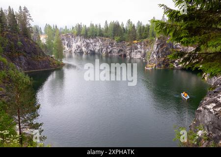 Ruskeala, Russie - 12 juin 2021 : paysage de Karelian avec des touristes dans un bateau naviguant à travers une ancienne carrière de marbre remplie d'eau souterraine Banque D'Images