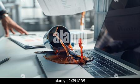 Office Manager renverse accidentellement du café chaud sur un ordinateur portable de travail avec présentation commerciale ou rapports financiers pour une grande entreprise. Concept d'échec ou de foirage dans Un lieu de travail Banque D'Images