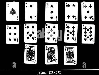 Un costume complet de pique jouant des cartes en noir sur un fond noir. Banque D'Images