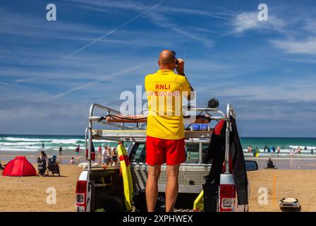 RNLI en service sur Watergate Bay, gardant une surveillance attentive pour tout accident et prêt pour des sauvetages rapides. Soyez fiers de ces bénévoles qualifiés pour leur travail Banque D'Images