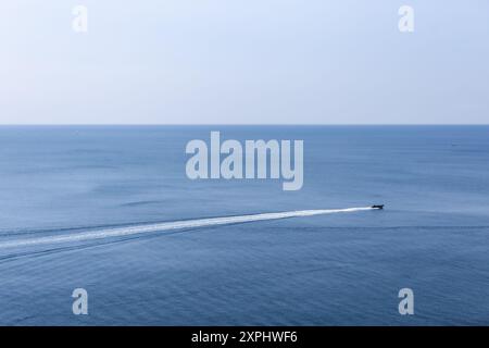 Petits bateaux de plaisance quittant Polperro laissant une traînée d'eau vive dans leur sillage. Les eaux calmes bleues transportent des passagers lors de courts trajets autour de la baie Banque D'Images