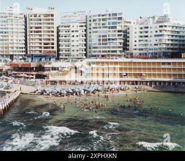 Une plage publique animée à Stanley Bay à Alexandrie, Egypte, Afrique. Les gens peuvent être vus nager et se détendre sous des parasols lors d'une journée ensoleillée de juin 2006. Banque D'Images