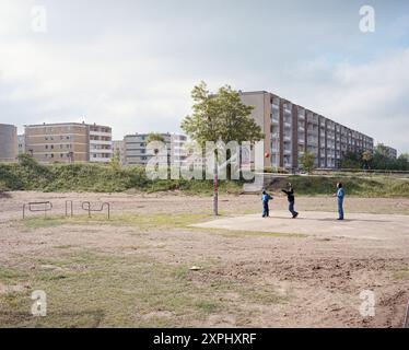 Image de 2003 montrant principalement vacant DDR Plattenbauten près de démolition à Eisenhüttenstadt, Allemagne. On voit des enfants jouer au basket-ball au premier plan, avec les bâtiments de la zone résidentielle VII en arrière-plan. Banque D'Images