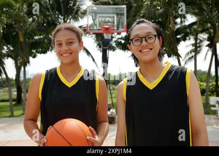 Joueurs de basket-ball souriants tenant un ballon en plein air Banque D'Images