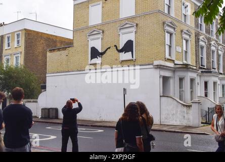 Londres, Royaume-Uni. 6 août 2024. Les gens prennent des photos d'une nouvelle œuvre d'art, confirmée par Banksy, sur un mur d'une maison à Chelsea. L'œuvre, représentant une paire d'éléphants, est la deuxième nouvelle œuvre d'art à Londres en deux jours par l'insaisissable artiste de rue. (Crédit image : © Vuk Valcic/SOPA images via ZUMA Press Wire) USAGE ÉDITORIAL SEULEMENT! Non destiné à UN USAGE commercial ! Crédit : ZUMA Press, Inc/Alamy Live News Banque D'Images