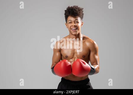 Jeune Boxer souriant tout en portant des gants rouges dans un cadre studio Banque D'Images