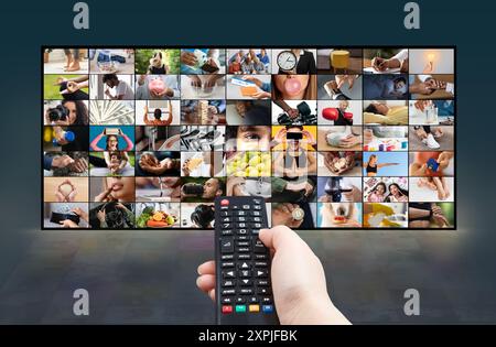 Une main tenant une télécommande devant un téléviseur Banque D'Images
