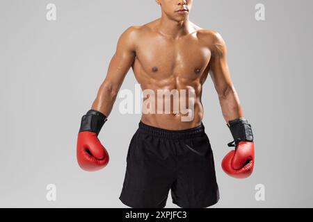 Jeune homme Boxer portant des gants rouges posant dans le studio Banque D'Images