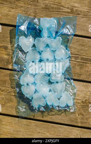 glaçons en forme de coeur en plastique bleu sur plancher de bois. Photo de haute qualité Banque D'Images