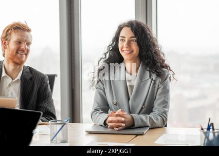 Femme d'affaires souriante dans la réunion de bureau moderne avec des collègues Banque D'Images