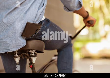 Portefeuille Tombant De Poche D'Afro Guy Sur Vélo Non Reconnaissable Banque D'Images