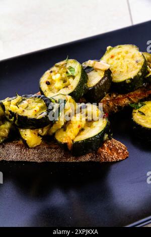 Courgettes sautées ou courgettes servies sur pain grillé au levain, vue surélevée, portrait en gros plan. Banque D'Images