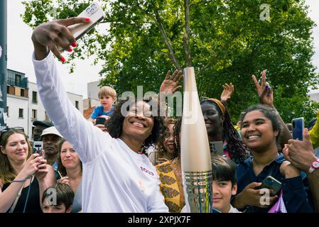 Nsimba Makonda M Buta, selfie avec les résidents locaux. Jeux Olympiques de Paris 2024. Le relais de la flamme olympique est passé par Montreuil ! Torche portée par Nsimba Makonda M Buta, une jeune habitante de Montreuil, devant la mairie de Montreuil. Paris, Montreuil le 25 juillet 2024. Photographie de Patricia Huchot-Boissier / Agence DyF. Banque D'Images