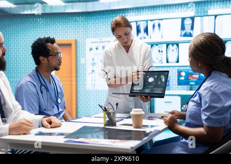 Équipe de spécialistes examinant les résultats de l'ecg lors d'une réunion dans une clinique privée, analysant le système cardiovasculaire sur une radiographie pour la prévention de la maladie. Consultation d'acquisitions et de dossiers cardiaques. Banque D'Images