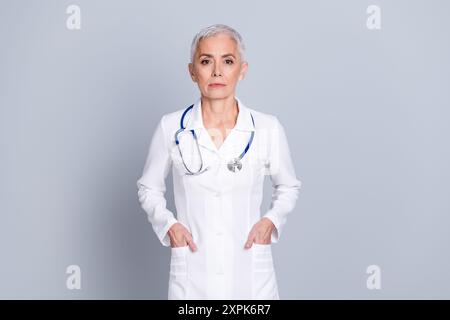 Photo de charmante femme médecin spécialiste qualifiée porter des diagnostics cliniques de robe blanche isolés sur fond de couleur grise Banque D'Images