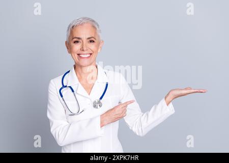 Photo de charmant médecin spécialiste qualifié femme chirurgien assurance medicare espace vide isolé sur fond de couleur grise Banque D'Images