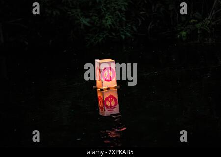 Salisbury, Wiltshire, Royaume-Uni, 6 août 2024. Campagne pour le désarmement nucléaire chandelles flottant reflétant la coutume japonaise des lanternes flottantes à la mémoire des morts. En souvenir de plus de 340 000 personnes qui sont mortes à la suite des bombes atomiques larguées sur Hiroshima et Nagasaki en août 1945, ainsi que de celles qui ont péri à la suite de tout le cycle nucléaire. Le flotteur de bougie comprenait des lanternes décorées par des enfants du lycée Kyoso à Hiroshima, au Japon, dans le cadre d'un engagement conjoint avec la CND pour débarrasser le monde des armes nucléaires. Crédit John Rose/Alamy Live News Banque D'Images