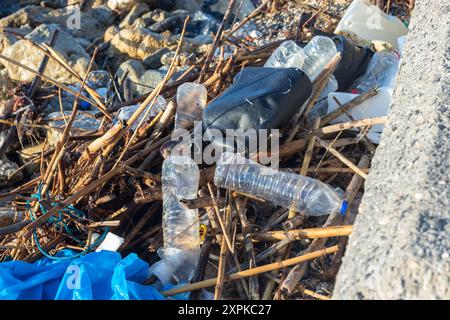 Plage polluée avec des bouteilles en plastique et des roseaux portés par les vagues. Apporté des matériaux apportés par les courants à la plage. Sac en plastique. Grèce. Banque D'Images