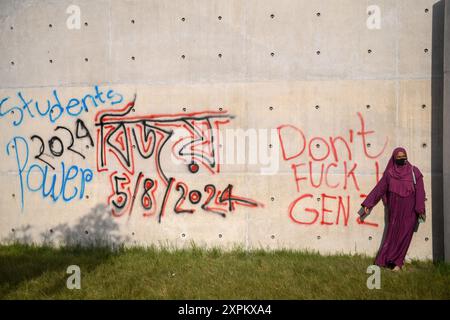 Dhaka, Bangladesh. 06 août 2024. Dhaka, Bangladesh. 06 août 2024. Un piéton se tient devant un mur endommagé suite à une manifestation. Le 5 août, Sheikh Hasina a démissionné de son poste de premier ministre du Bangladesh et a pris l'avion du Bangladesh pour l'Inde. Crédit : SOPA images Limited/Alamy Live News Banque D'Images