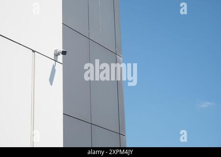Une caméra de surveillance moderne est installée sur un bâtiment de conception architecturale minimaliste Banque D'Images