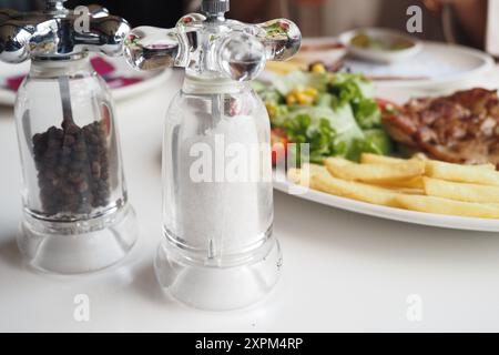 Délicieux salière et poivrière accompagnés d'un délicieux repas présenté sur table Banque D'Images