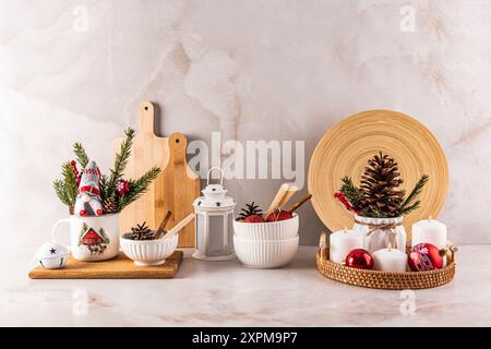 Décorations de Noël et de Noël sur le comptoir en marbre de la cuisine pour les vacances. bougies blanches, grand cône de cèdre, branches d'épinette. Vue de face. Banque D'Images