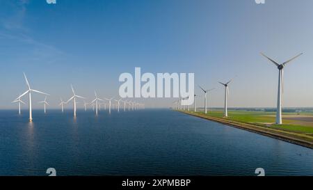 Aux pays-Bas, les éoliennes sont hautes le long du bord de l'eau et exploitent les énergies renouvelables sous un ciel bleu clair. Parc éolien Westermeerdijk Ijsselmeer pays-Bas Banque D'Images