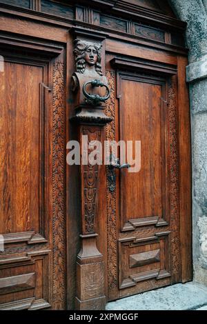 Une porte en bois magnifiquement conçue présente des sculptures élaborées et une poignée unique, mettant en valeur le savoir-faire typique de l'architecte européen historique Banque D'Images