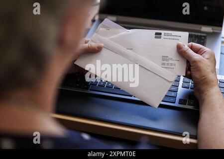 Eine aeltere Frau oeffnet einen Brief der Deutschen Rentenversicherung. Berlin, 05.08.2024. Berlin Deutschland *** une femme âgée ouvre une lettre de Deutsche Rentenversicherung Berlin, 05 08 2024 Berlin Allemagne Copyright : xKiraxHofmann/photothek.dex Banque D'Images