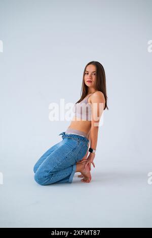 une fille aux cheveux longs qui coulent s'assoit sur le sol et regarde vers l'avant Banque D'Images