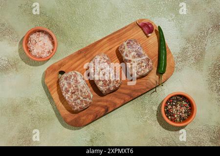 Vue aérienne des galettes de bœuf cru ou d'agneau - Apkhazura sur planche à découper en bois Banque D'Images