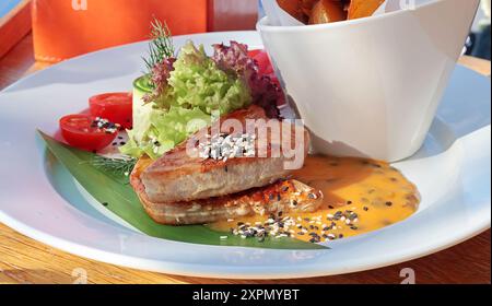 Thon grillé avec légumes frais et sauce, pommes de terre rôties. Nourriture et plats au restaurant. Nourriture utile et colorée. Banque D'Images