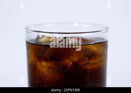 Un verre isolé de cola noir avec de la glace est rempli sur fond blanc Banque D'Images