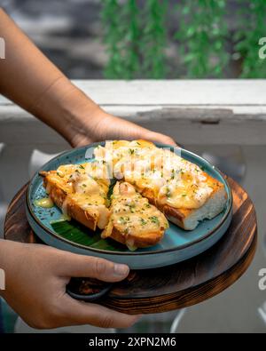 Une assiette de deux sandwichs ouverts avec une sauce crémeuse au fromage et une garniture d'herbes sur une assiette bleue Banque D'Images