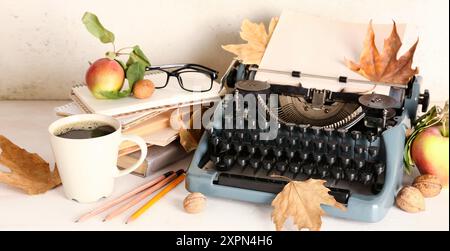 Machine à écrire vintage, pommes, livres, tasse de café et feuilles d'automne sur fond blanc Banque D'Images