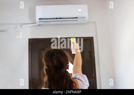 La femme allume le climatiseur Banque D'Images