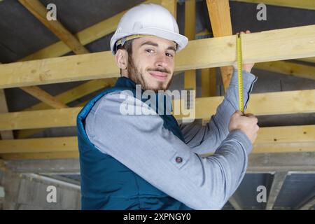 portrait de travailleur de la construction mesurant des planches sur le chantier de construction Banque D'Images