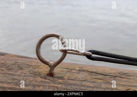 Anneau d'amarrage pour bateaux dans la pierre avec carabine et corde noire du bateau, rivage pierreux, nœud de corde, Finlande Banque D'Images