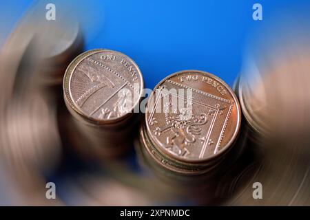 L'argent tourne autour, un morceau d'un penny et deux penny dans un flou de rotation sur d'autres pièces. Espace d'en-tête Banque D'Images